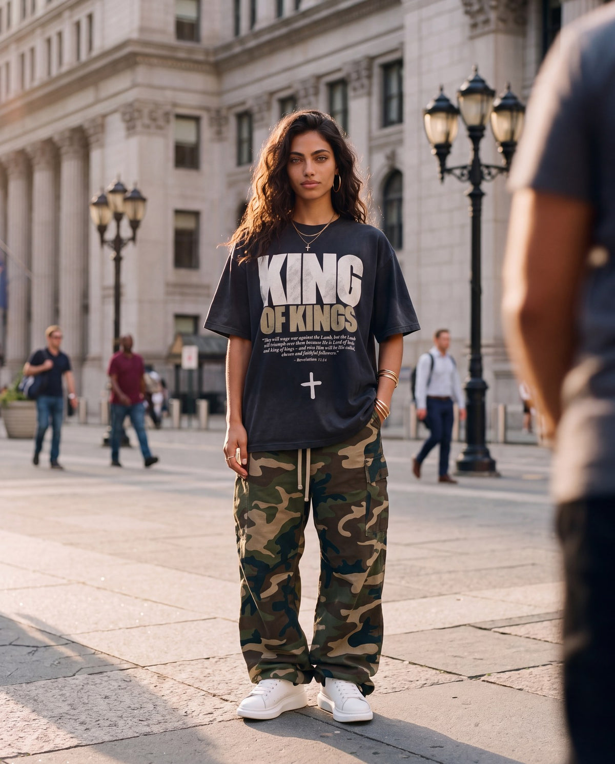 Woman in a washed black King of Kings tee and camo pants on a city square, Vintage & Sunfaded collection