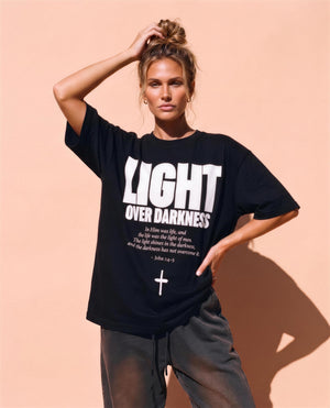Light Over Darkness tee, black, front print, woman, hand in hair thigh up