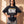 Daughter of the King faded black tee, front print, woman with wet look hair and both hands on her hips, worn over washed cargo pants