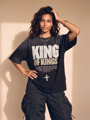 King of Kings faded black tee, front print, woman with a hand in her curly hair and one on her hip, styled with baggy cargo pants