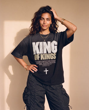 King of Kings faded black tee, front print, woman with a hand in her curly hair and one on her hip, styled with baggy cargo pants