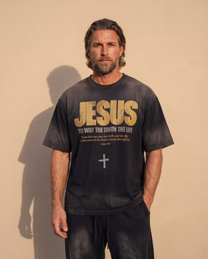 Jesus the Way the Truth the Life faded black tee, front print, man with a beard and hands in his pockets against a sunlit wall