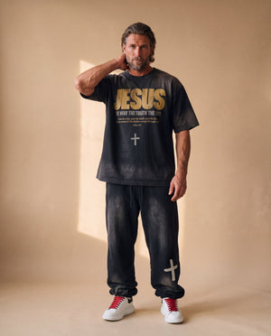 Jesus the Way the Truth the Life faded black tee, full body view of a man with a hand behind his neck in matching sweatpants and sneakers