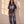 In the Beginning God faded black tee, full body view of a woman in baggy faded jeans and sneakers, one hand in her pocket by a sunlit wall