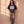 Heart of a Lion faded black tee, full body view of a woman leaning on a sunlit wall in striped track pants and sneakers