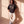 Heart Wide Open faded black tee, full body view of a woman leaning on a sunlit wall, legs crossed, in sweatpants and sneakers