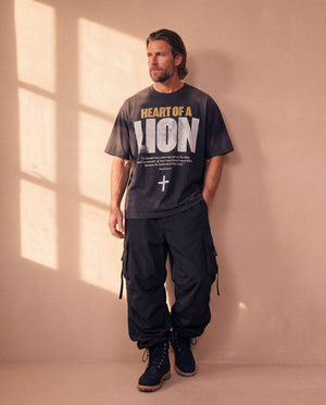Heart of a Lion faded black tee, full body view of a man in cargo pants and work boots, hands in his pockets, Christian streetwear