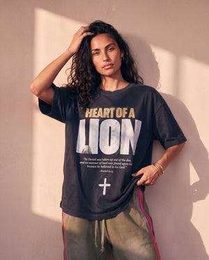 Heart of a Lion faded black tee, front print, woman leaning on a wall with a hand in her hair and one at the hem, Christian streetwear