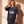 Jesus Is King faded black tee, smiling woman tucking her hair behind her ear, oversized fit with dropped shoulders