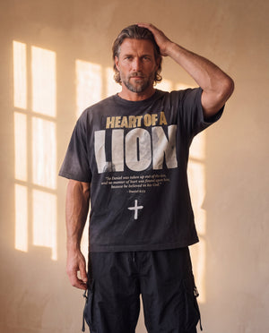 Heart of a Lion faded black tee, front print, man with a hand in his hair, thigh up, the oversized fit hanging loose