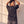 In the Beginning God faded black tee, back view of a woman with both hands in her hair, small crown logo below the collar