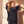 Jesus Is King faded black tee, back view of a woman with both hands in her hair, glancing over her shoulder at the camera
