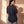 Daughter of the King faded black tee, back view of a woman with a hand on her shoulder, small crown logo below the collar