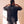 Jesus Is King faded black tee, back view of a man with braids holding the collar, crown logo centred under the neckline