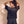 King of Kings faded black tee, back view of a woman with both hands in her hair, looking over her shoulder, crown logo below the collar