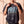 Pray Until Something Happens faded black tee, front print, smiling woman holding the collar, cross necklace above the PRAY lettering