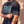 Pray Until Something Happens faded black tee, close up on a man's arm pinching the sleeve, PRAY UNTIL SOMETHING HAPPENS lettering beside it