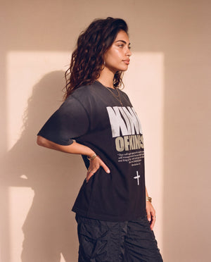 King of Kings faded black tee, side profile of a woman with a hand on her hip, showing the boxy cut and the dropped shoulder