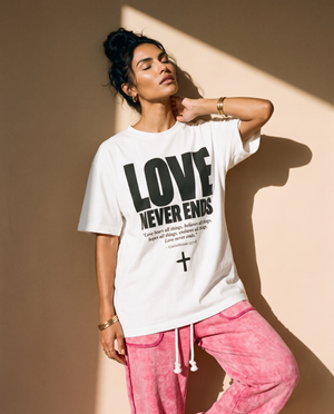 Love Never Ends tee, white, front print, woman, leaning on wall thigh up