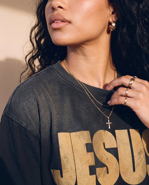 Jesus the Way the Truth the Life faded black tee, close up of a woman's hand at the collar, cross necklace above the JESUS lettering