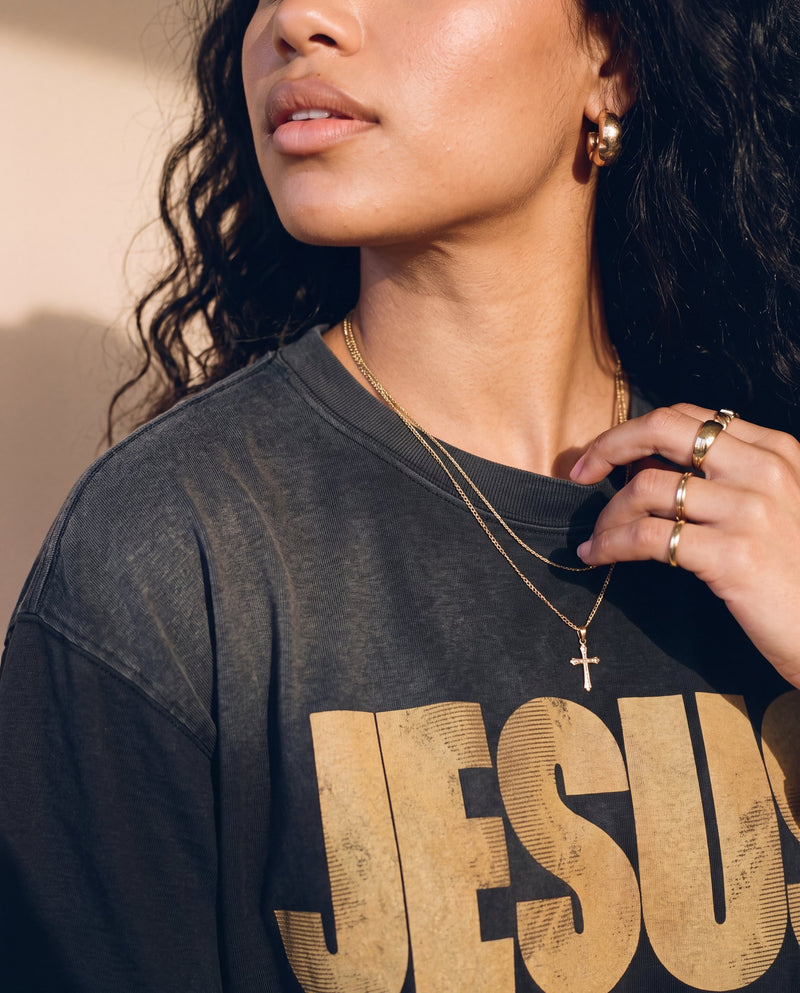 Jesus the Way the Truth the Life faded black tee, close up of a woman's hand at the collar, cross necklace above the JESUS lettering