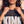 King of Kings faded black tee, close up of a woman holding the ribbed collar, cross necklace and hoop earrings above KING