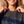 Jesus Is King faded black tee, close up of a woman holding the ribbed collar, cross necklace above the distressed JESUS lettering