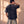 Pray Until Something Happens faded black tee, back view of a man with a hand on the side of his neck, small crown logo below the collar