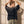 Pray Until Something Happens faded black tee, back view of a woman with both hands in her hair bun, small crown logo below the collar