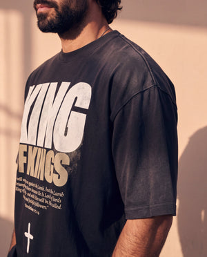 King of Kings faded black tee, close up on a man's shoulder and chest, the KING OF KINGS lettering and verse in sharp focus