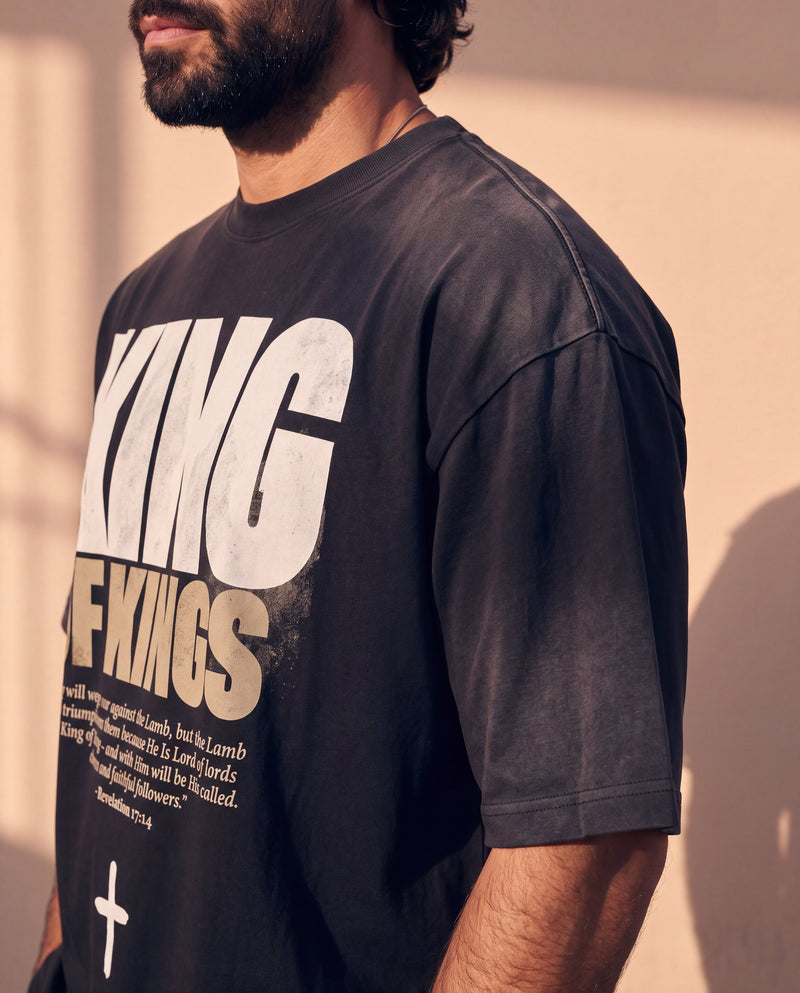 King of Kings faded black tee, close up on a man's shoulder and chest, the KING OF KINGS lettering and verse in sharp focus