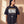Daughter of the King faded black tee, front print, woman looking to the side by a sunlit wall, the oversized fit hanging loose