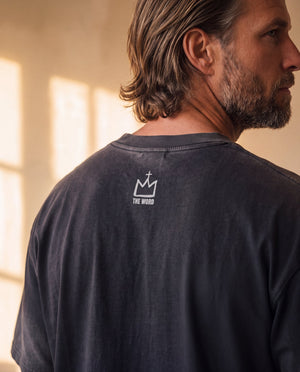 Heart of a Lion faded black tee, close up of the back neckline on a man, crown logo and THE WORD below the ribbed collar