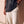 Heart Wide Open faded black tee, close crop on a woman lifting the hem over THE WORD sweatpants, the verse and cross above