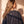 Jesus Is King faded black tee, back view of a woman with long wavy hair over one shoulder, small crown logo under the neckline