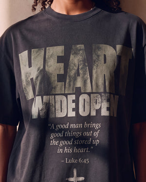 Heart Wide Open faded black tee, close up of the front print on a woman, HEART WIDE OPEN lettering and the Luke 6:45 verse