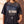 Jesus Is King faded black tee, front print in full on a woman with a cross necklace, John 1:1 verse and cross, Christian streetwear