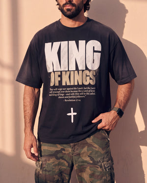 King of Kings faded black tee, close crop on a man's torso, the Revelation 17:14 verse and cross with one hand at the hem