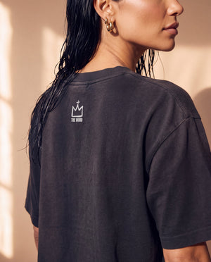 Daughter of the King faded black tee, close up of the back neckline on a woman, crown logo and THE WORD below the ribbed collar
