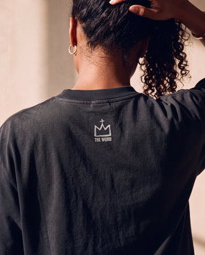 Heart Wide Open faded black tee, close up of the back neckline on a woman, crown logo and THE WORD below the ribbed collar