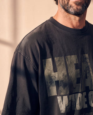 Heart Wide Open faded black tee, close up on a man's shoulder and chest, the sunfaded sleeve and the distressed HEART lettering