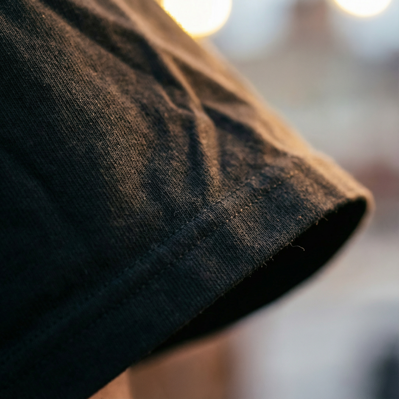 Fabric detail, close up of the sleeve hem on a black tee