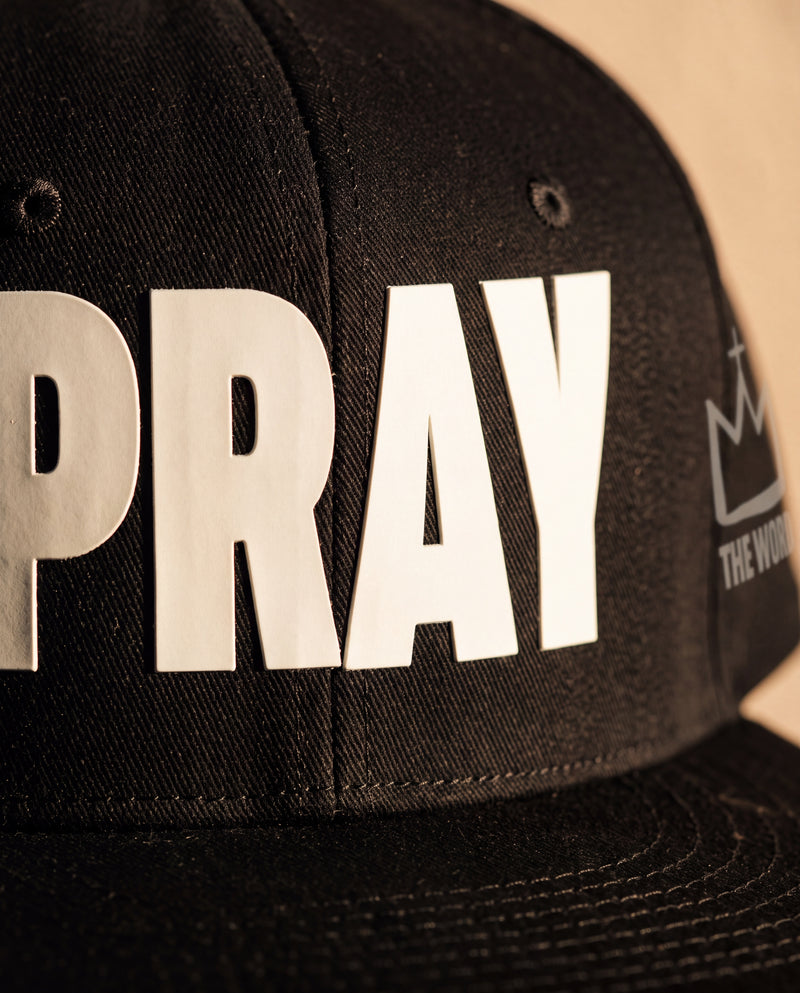 PRAY snapback cap, close-up of the raised front print