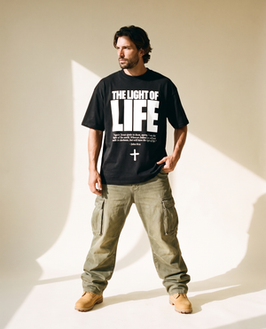 The Light of Life tee, black, front print, man, hand on hem full body