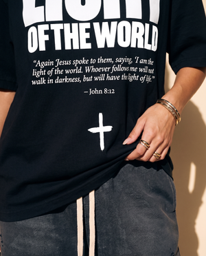 Light of the World tee, black, front print, woman, hand on hem close up
