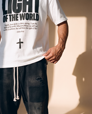 Light of the World tee, white, front print, man, hand on hem close up