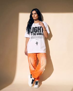 Light of the World tee, white, front print, woman, leaning on wall full body