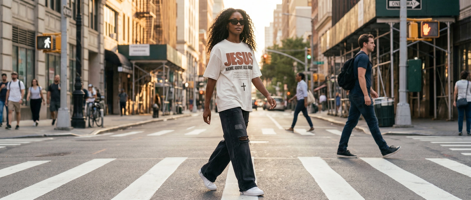 Woman in a white JESUS tee crossing a city street