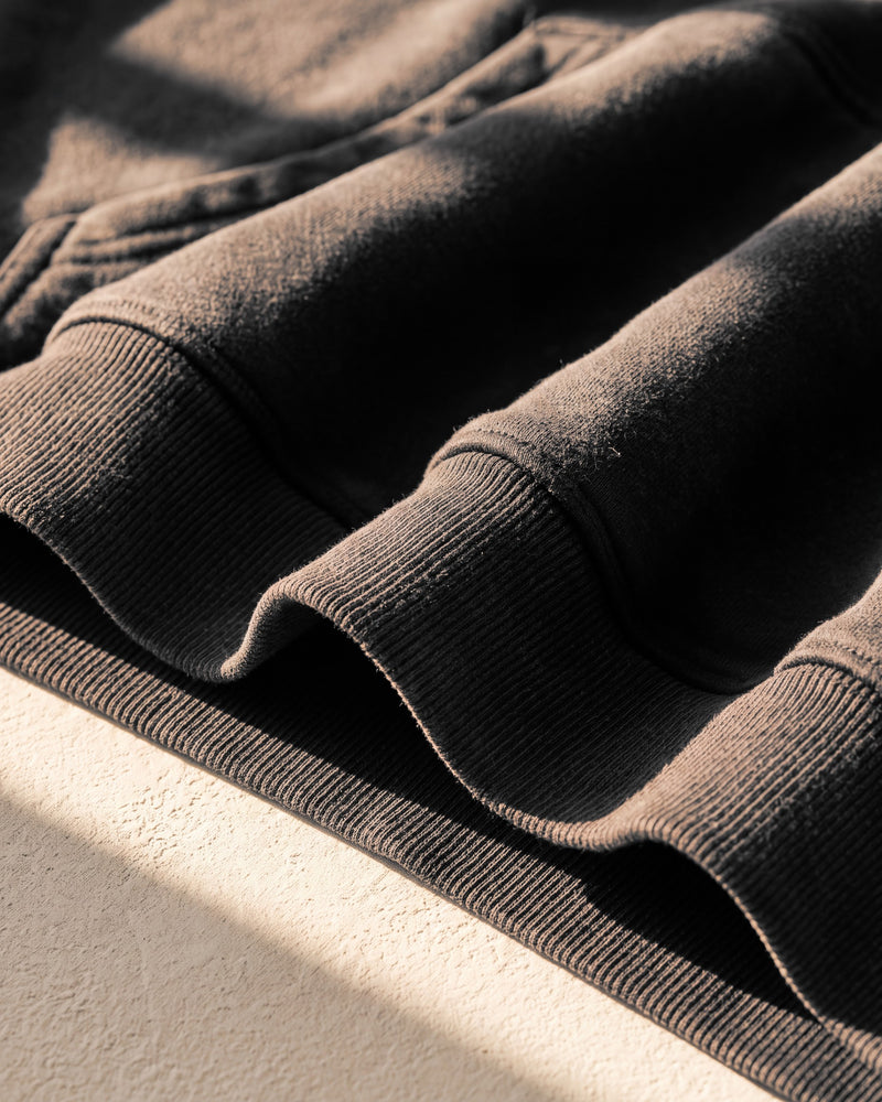 Black faded hoodie, ribbed hem, close-up