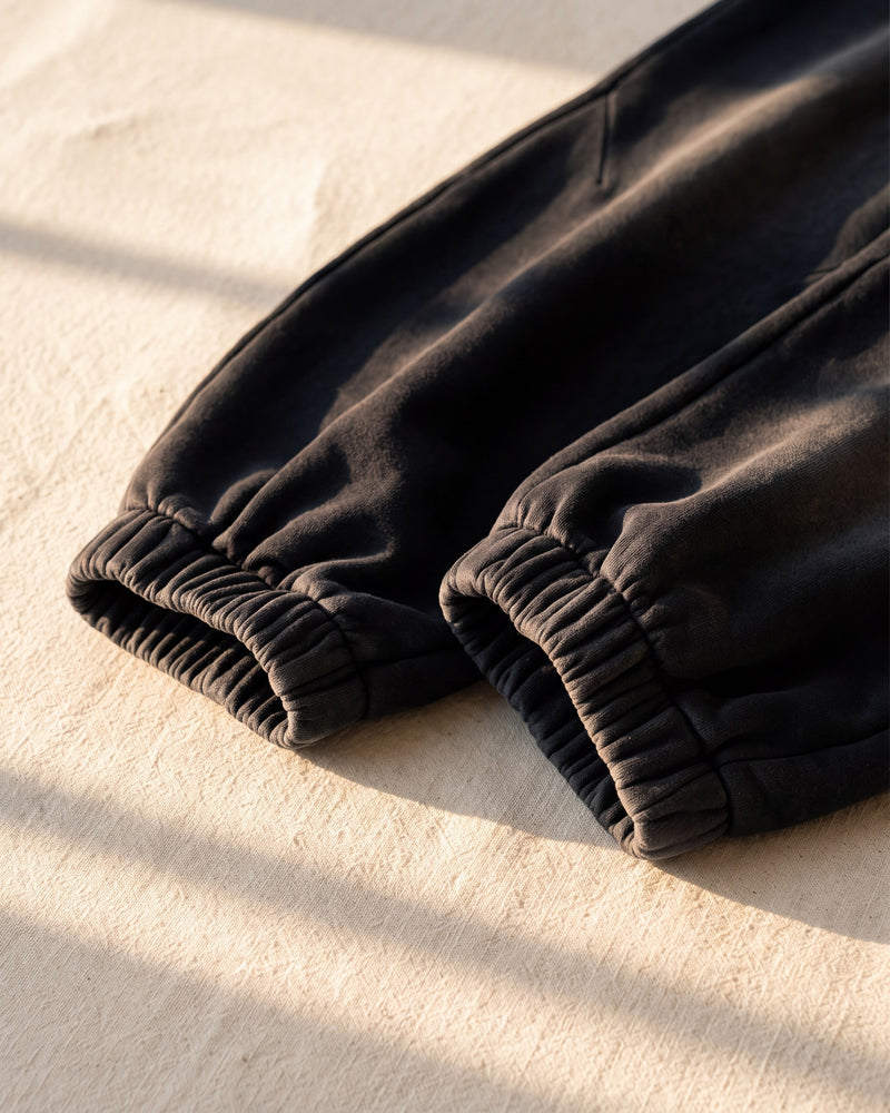 Elastic ankle cuffs on black heavyweight The Word sweatpants in warm sunlight